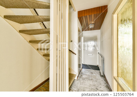 A well-lit staircase hallway featuring neutral colors, inviting carpet, and clean lines, ideal for modern interior designs and home aesthetics. 125503764