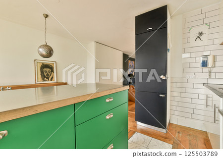 Stylish modern kitchen featuring vibrant green cabinets, a minimalist design, and contemporary decor elements, creating an inviting and functional space. 125503789