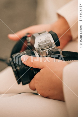 Close-Up of Hands Holding a Vintage Camera Outdoors 125503817