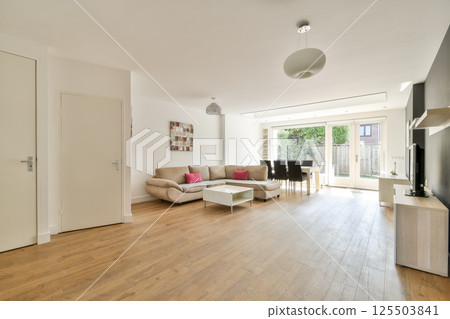 Contemporary living room featuring a cozy couch, sleek furniture, and a design that combines functionality with aesthetic appeal for an inviting atmosphere. 125503841