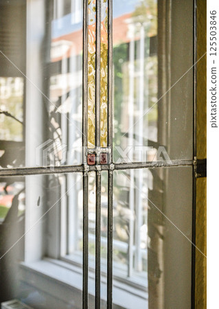 An intricate stained glass window featuring geometric patterns and vibrant colors, reflecting sunlight beautifully and enhancing the indoor ambiance. 125503846