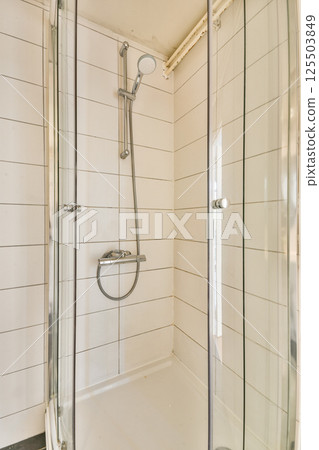 A contemporary shower stall featuring glass doors, sleek fixtures, and clean lines, set in a bright and minimalist bathroom environment. 125503849