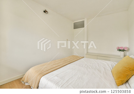 A cozy minimalist bedroom featuring a neatly made bed with soft beige linens, natural wooden floor, and simple wall decor for a calming atmosphere. A cozy minimalist bedroom featuring a neatly made bed with soft beige linens, natural wooden floor, and simple wall decor for a calming atmosphere. 125503858