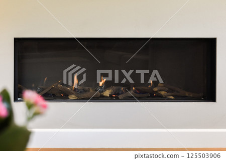 A sleek, modern fireplace adds warmth and style to a contemporary living space, framed by minimalistic decor and soft lighting. A sleek, modern fireplace adds warmth and style to a contemporary living space, framed by minimalistic decor and soft lighting. 125503906