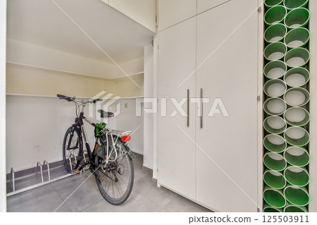 A sleek, modern storage area features a bicycle alongside stylish storage cabinets, highlighting efficient use of space and contemporary design. 125503911