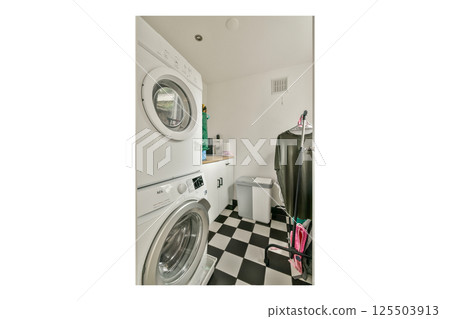 A modern laundry room featuring stacked washer and dryer appliances surrounded by minimalist decor. The floor is designed with a striking black and white checkered pattern. A modern laundry room featuring stacked washer and dryer appliances surrounded by minimalist decor. The floor is designed with a striking black and white checkered pattern. 125503913