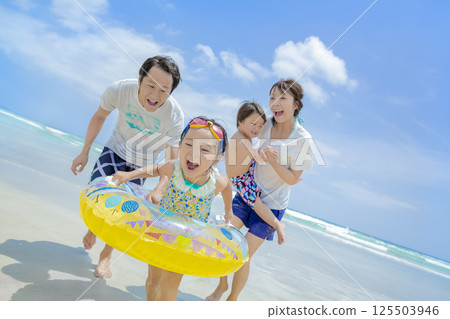 A family of four playing in the summer sea 125503946