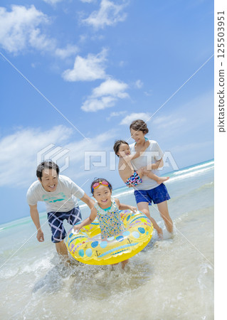 A family of four playing in the summer sea 125503951