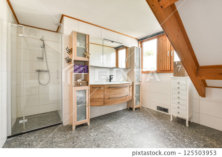 Stylish and functional bathroom featuring a glass shower, wooden cabinetry, and contemporary decor elements that enhance its spacious feel. Stylish and functional bathroom featuring a glass shower, wooden cabinetry, and contemporary decor elements that enhance its spacious feel. 125503953