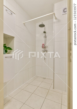 A sleek and clean shower room featuring white tiles and minimal decor, creating an open and fresh atmosphere for relaxation. A sleek and clean shower room featuring white tiles and minimal decor, creating an open and fresh atmosphere for relaxation. 125503977