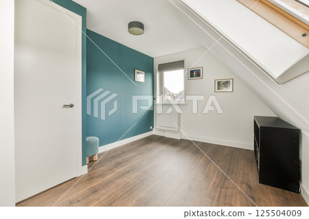 Bright, modern interior featuring a decorative teal wall, wooden flooring, and natural light pouring in through the windows, creating a serene atmosphere. 125504009