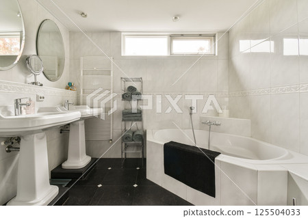 A stylish and spacious bathroom featuring modern fixtures, a luxurious bathtub, and elegant design elements that create a serene atmosphere. 125504033