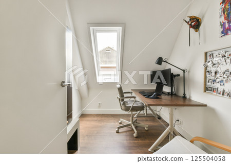 A stylish and functional home office featuring minimalistic furniture, ample natural light, and a cozy workspace setup to enhance productivity and comfort. A stylish and functional home office featuring minimalistic furniture, ample natural light, and a cozy workspace setup to enhance productivity and comfort. 125504058