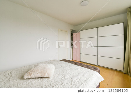 A sleek, modern bedroom featuring a minimalist bed, soft textures, and a stylish wardrobe, creating a serene and organized space perfect for relaxation. A sleek, modern bedroom featuring a minimalist bed, soft textures, and a stylish wardrobe, creating a serene and organized space perfect for relaxation. 125504105