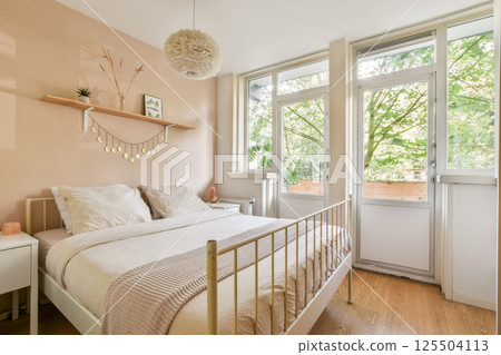 A serene bedroom featuring soft colors, large windows for natural light, and minimalist decor, creating a warm and inviting atmosphere perfect for relaxation. 125504113