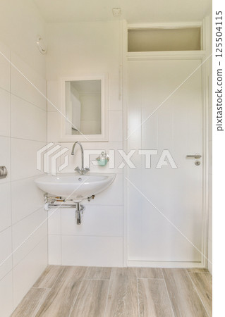 A sleek and modern bathroom featuring a stylish sink, clean lines, and neutral tones, creating a tranquil and spacious ambiance. 125504115