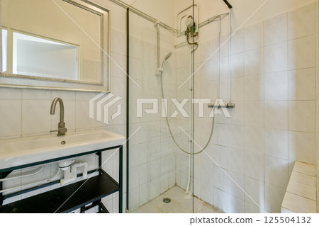 A sleek modern bathroom featuring a glass shower enclosure, stylish fixtures, and minimalist design elements. Perfect for contemporary home aesthetics. 125504132