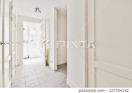 an empty hallway with white walls and tile flooring photo taken from the front door, looking towards the entrance 125504192