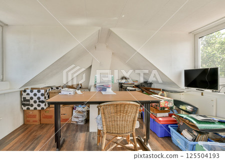 A well-organized home office featuring a large desk, comfortable chair, and ample storage. Sunlight enhances the ambiance, creating a productive workspace. 125504193