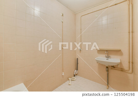 A clean, minimalistic bathroom featuring pink tiled walls and a simple sink setup. The space reflects a modern yet understated design aesthetic. 125504198