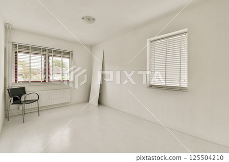 Bright, minimalist interior showcasing a simple room design featuring a chair, window with blinds, and light walls, creating a serene and open atmosphere. 125504210