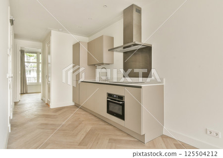 Stylish modern kitchen featuring sleek cabinetry, contemporary appliances, and natural light streaming through large windows. A perfect blend of functionality and aesthetics. 125504212