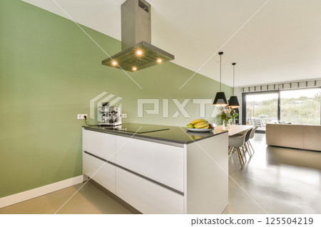 A sleek and contemporary kitchen featuring minimalist cabinetry and an island with modern appliances, perfect for stylish cooking and dining. 125504219