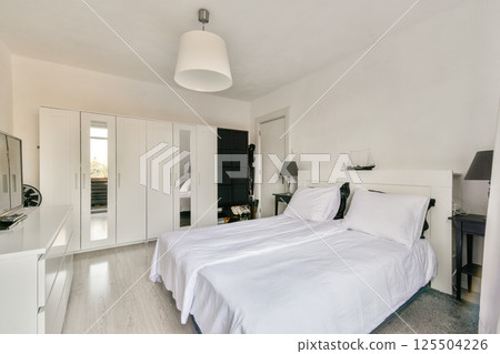 A sleek, modern bedroom design featuring a comfortable bed, minimalist furniture, and a well-organized wardrobe, perfect for contemporary living. 125504226