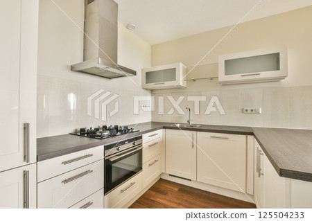 A stylish modern kitchen featuring sleek cabinetry, a gas stove, and minimalist design elements. The space blends functionality with contemporary aesthetics for a complete look. 125504233