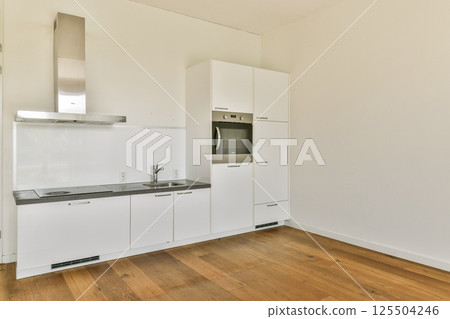 Stylish and minimalistic kitchen featuring sleek cabinetry, integrated appliances, and a spacious layout enhancing the modern aesthetic. 125504246