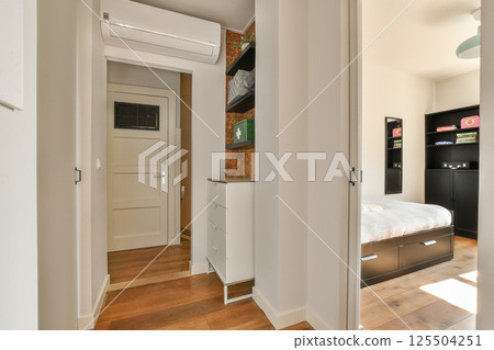 Bright and airy modern interior hallway showcasing minimalist design elements and ample natural light, leading to a cozy bedroom area. 125504251