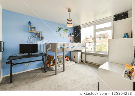 A stylish kids bedroom featuring a bunk bed, blue walls, and a cozy play area. The room includes furniture and decorations that create an inviting atmosphere. 125504258