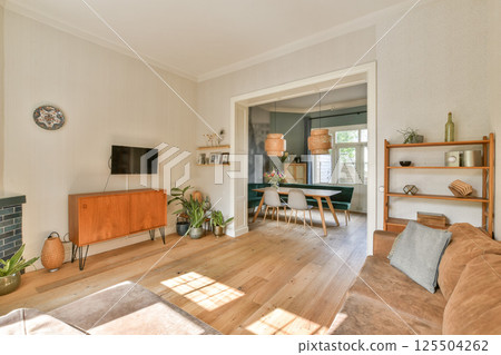 A stylish modern living room featuring wooden flooring, minimalist furniture, and tasteful decor elements that enhance comfort and aesthetic appeal. 125504262