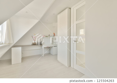 a bedroom with white walls and wooden flooring, an open door to the left is a small desk on the right side 125504263