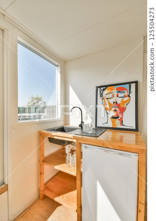 Bright and airy space featuring a wooden countertop, sink, and an artistic painting, showcasing contemporary design and natural light. Bright and airy space featuring a wooden countertop, sink, and an artistic painting, showcasing contemporary design and natural light. 125504273