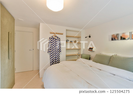 A well-lit modern bedroom featuring elegant bedding, stylish decor, and minimalist design elements that create a peaceful atmosphere. 125504275