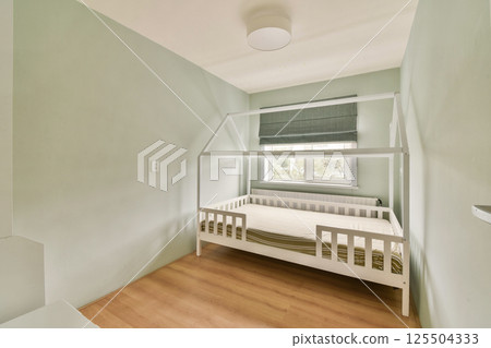 A serene minimalistic bedroom featuring a simple bunk bed, light green walls, and natural light streaming through a window, creating a calm atmosphere. 125504333