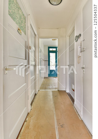 A bright and spacious indoor hallway featuring white doors and natural light streaming through, creating a welcoming atmosphere. 125504337