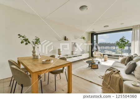 A contemporary living room showcasing minimalist decor with natural light, wooden furniture, and elegant furnishings creating a welcoming ambiance. 125504360