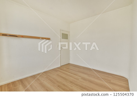A serene, minimalist empty room featuring a wooden rack against a white wall and light wooden flooring, emphasizing simplicity and spaciousness. A serene, minimalist empty room featuring a wooden rack against a white wall and light wooden flooring, emphasizing simplicity and spaciousness. 125504370