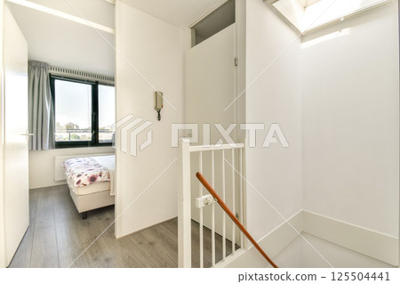 Bright and open staircase leading to a modern bedroom, showcasing a minimalist aesthetic with white walls and natural light. 125504441