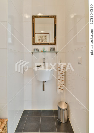 A minimalist bathroom showcasing sleek white tiles, a stylish mirror, and contemporary fixtures, creating an elegant and fresh atmosphere. 125504550