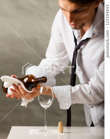 Man waiter pouring wine into glass. Man waiter pouring wine into glass. 125504843