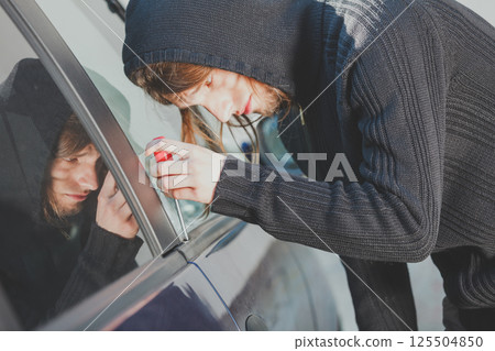 Thieft man holding screwdriver breaking into car Thieft man holding screwdriver breaking into car 125504850