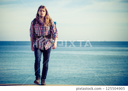 Man hiker with backpack tramping by seaside 125504905