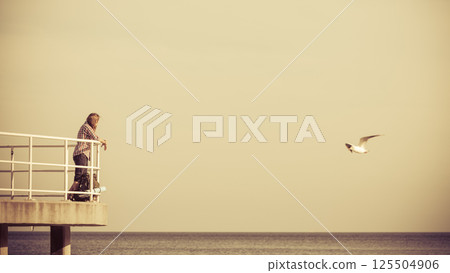Man hiker with backpack on pier, sea landscape 125504906