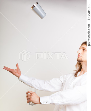 Skilled bartender juggling with glass. 125504909