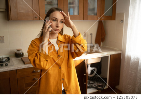 Woman seeks help for leaky sink in cozy kitchen during a busy morning 125505073