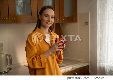 Woman drinking hot beverage in kitchen 125505082