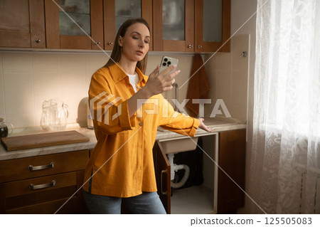 Woman using smartphone video call showing broken sink drain to plumber Woman using smartphone video call showing broken sink drain to plumber 125505083